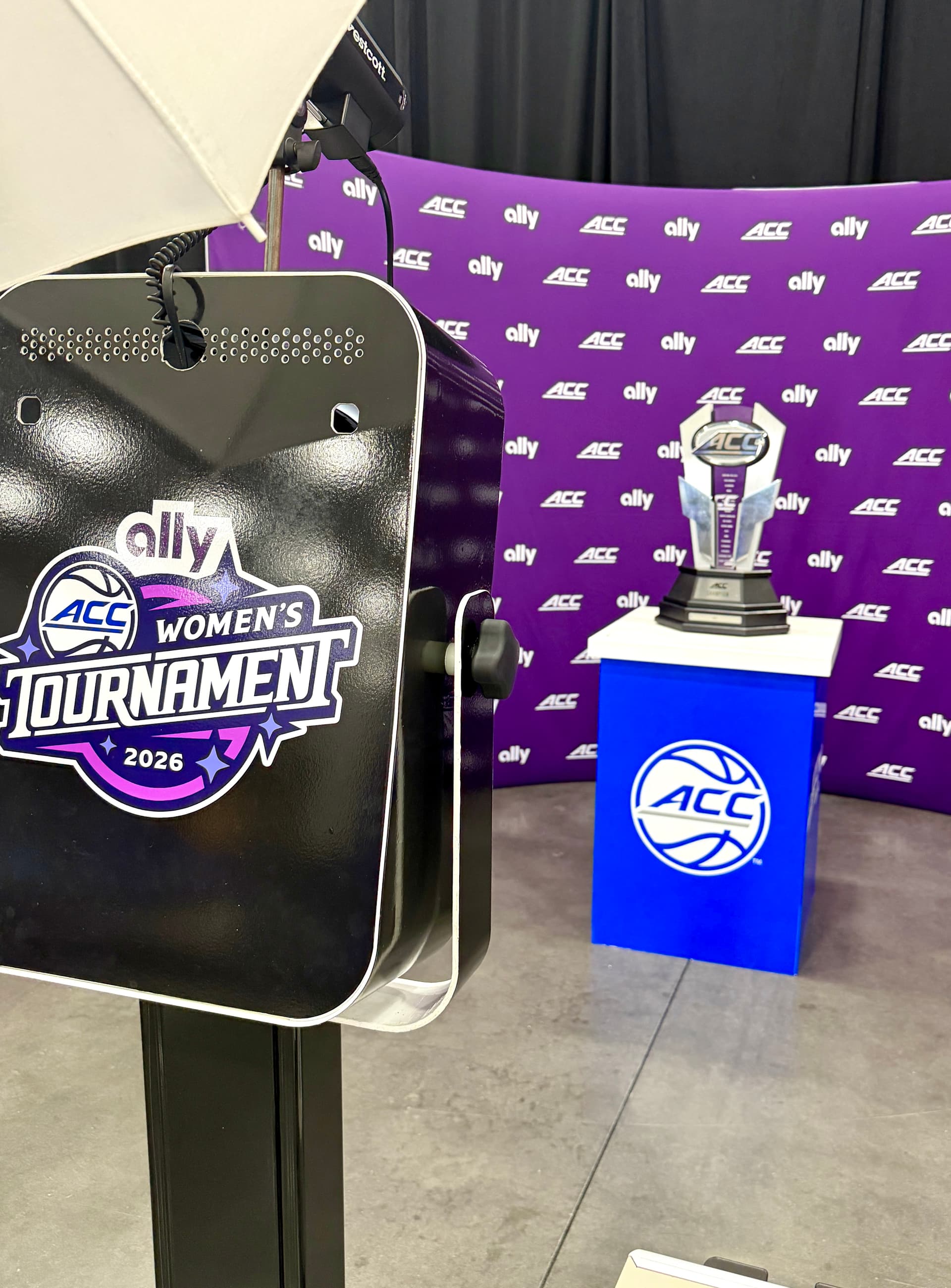 Fan posing with the ACC Women's trophy in a branded Ally photo op